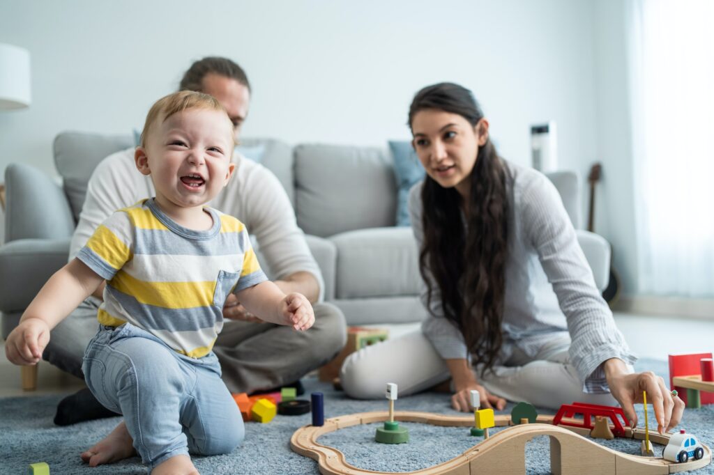 Caucasian happy loving parent play with baby toddler in living room.